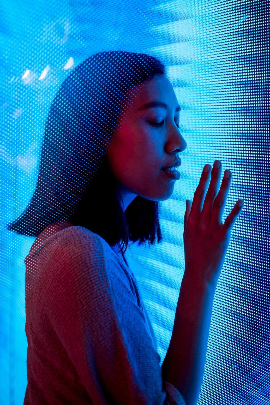 Girl holding hand against screen illuminated with colors